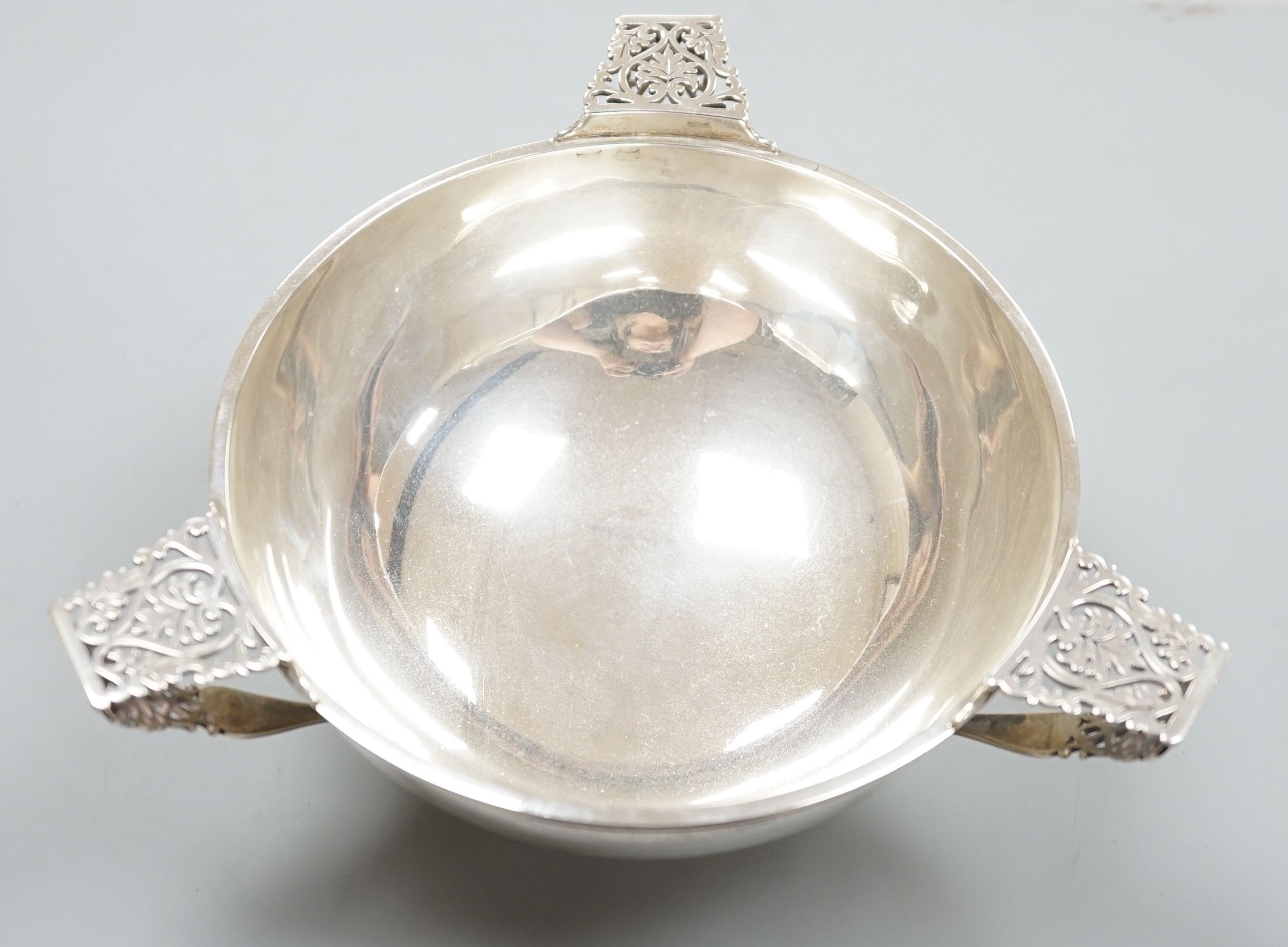An Edwardian silver circular bowl, with three piece harp shape handles, Goldsmiths & Silversmiths Co Ltd, London 1906, on pedestal foot, diameter 16.25cm, 14oz.